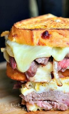 a close up of a sandwich on a cutting board with cheese and meat in it