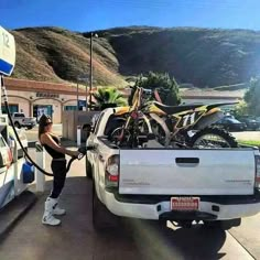 a woman pumping gas into her truck at a gas station