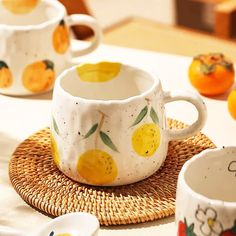 two cups with lemons painted on them are sitting on a wicker place mat