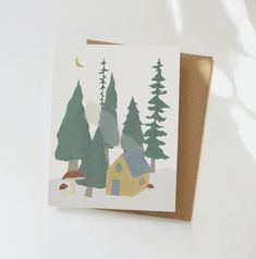 a card with a house and trees on it, in front of a white background