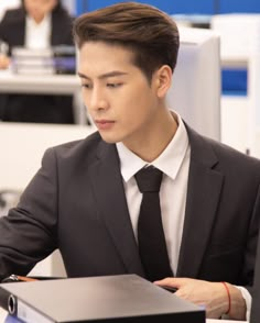 a man in a suit and tie sitting at a desk with a laptop on it