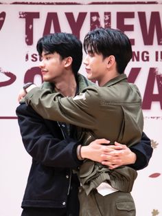 two young men hugging each other in front of a sign