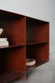 a shelf with some books on it and a bowl sitting on top of the bookcase