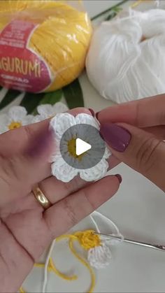 a person holding a flower in their hand with crochet work on the background