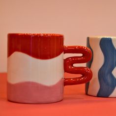 two coffee mugs sitting next to each other on a table