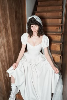 a woman in white dress sitting on stairs