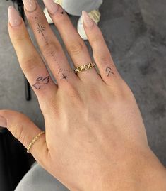 a woman's hand with tattoos on it and a gold band around the ring