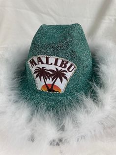 a green hat with palm trees and the word mallibu on it sitting on a white background