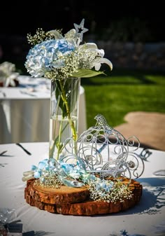 a vase filled with white flowers sitting on top of a wooden slice next to a table