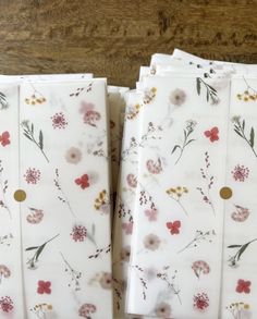 four napkins with floral designs on them sitting on a wooden table next to each other