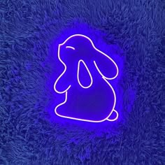 a purple neon sign sitting on top of a blue fuzzy carpet next to a cell phone