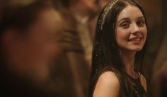 a young woman wearing a tiara standing in front of other people at a party