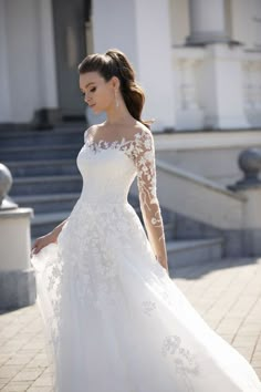 a woman in a white wedding dress is standing outside