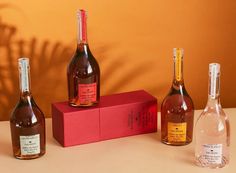 three bottles of wine sitting on top of a pink box