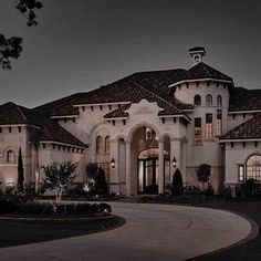 a large white house with lots of windows and lights on it's front entrance