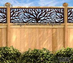 a wooden fence with an iron tree design on the top and bottom panel, in front of some bushes