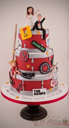 a three tiered cake with people on top and various stickers all over it