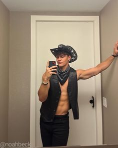 a shirtless man taking a selfie in front of a mirror wearing a cowboy hat