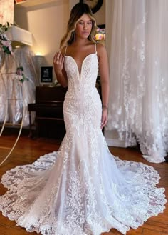 a woman in a white wedding dress standing on a wooden floor and looking at the camera