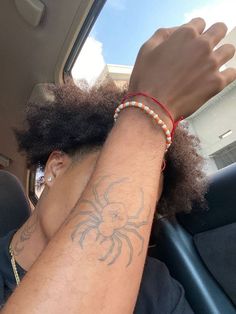 a man with his hand on the back seat of a car, wearing a bracelet that has a spider tattooed on it