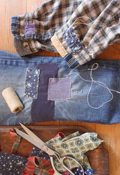 several different types of fabric and scissors on a wooden table with some sewing supplies in front of them