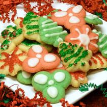 decorated cookies on a white plate with red and green decorations around them, including leaves