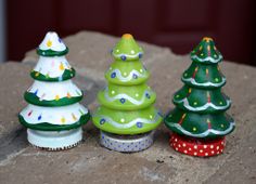 three ceramic christmas trees sitting on top of a rock