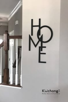 a metal sign that says home on the side of a wall next to stairs in a house