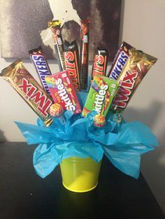 a yellow cup filled with candy and wrapped in blue paper on top of a table