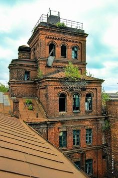 an old brick building with ivy growing on the roof