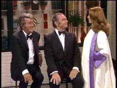 three men in tuxedos are sitting on a chair and talking to each other