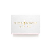 a white box with gold foil on the front and bottom that says, olvia & marcus