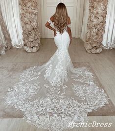 a woman in a white wedding dress is looking down at the floor with her back to the camera