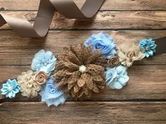 the flowers are made out of fabric and brown ribbon on top of wood planks