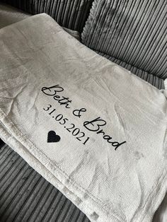 a white towel with black ink on it sitting on top of a couch next to pillows