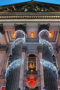 an ornate building decorated with christmas lights and wreathed columns in front of the entrance