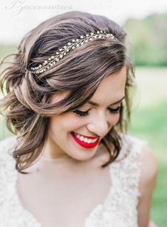 a woman in a wedding dress smiling and wearing a headband with leaves on it