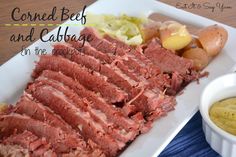 corned beef and potatoes on a white platter with mustard in a small bowl