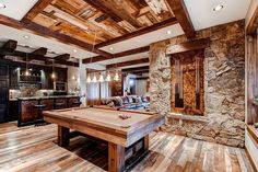 a pool table in the middle of a room with wood flooring and stone walls