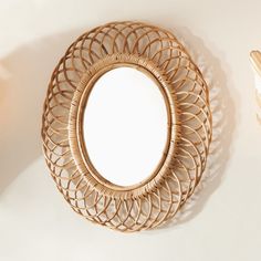 a round mirror sitting on top of a white wall next to a wooden table lamp