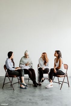 four women sitting in chairs talking to each other