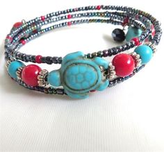 This memory wire wrap bracelet features a Turquoise Magnesite stone carved in the shape of a turtle. There are Red Coralbeadsand square blue Magnesite stones. The red and the blue represent Mother Earth and Father Sky. The two elements are necessary to form a Yin Yang balance in life. The bracelet is Average in size, fits loosely on a 6 61/2 wrist and a bit more snugly on a 7 71/2 wrist. The carved turtle is in length. There are blue iridescent seed beads and two black crysta... Carved Turtle, Yin Yang Balance, Memory Wire Jewelry, Balance In Life, Memory Wire Wrap Bracelets, Wire Wrap Bracelet, Stone Bead Jewelry, Junk Jewelry, Beaded Necklace Designs