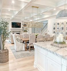 a large open concept kitchen and dining room with white cabinets, marble countertops and wooden flooring