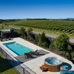 an outdoor hot tub next to a large swimming pool in the middle of a field