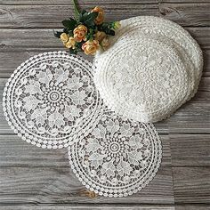 three white doily on top of a wooden floor next to a vase with flowers