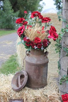 a vase with flowers in it sitting on some hay