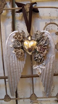 an angel decoration hanging from the side of a door with flowers and leaves on it