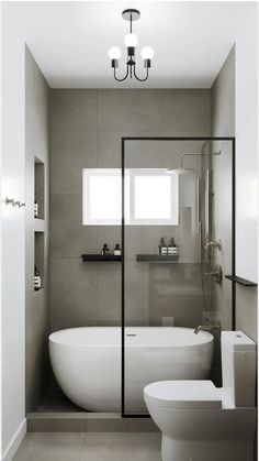 a white bath tub sitting next to a toilet in a bathroom under a light fixture