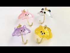 four different colored bears holding umbrellas in their hands on a white surface with gold chains