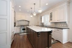 a large kitchen with an island in the middle of it and white cabinets on both sides